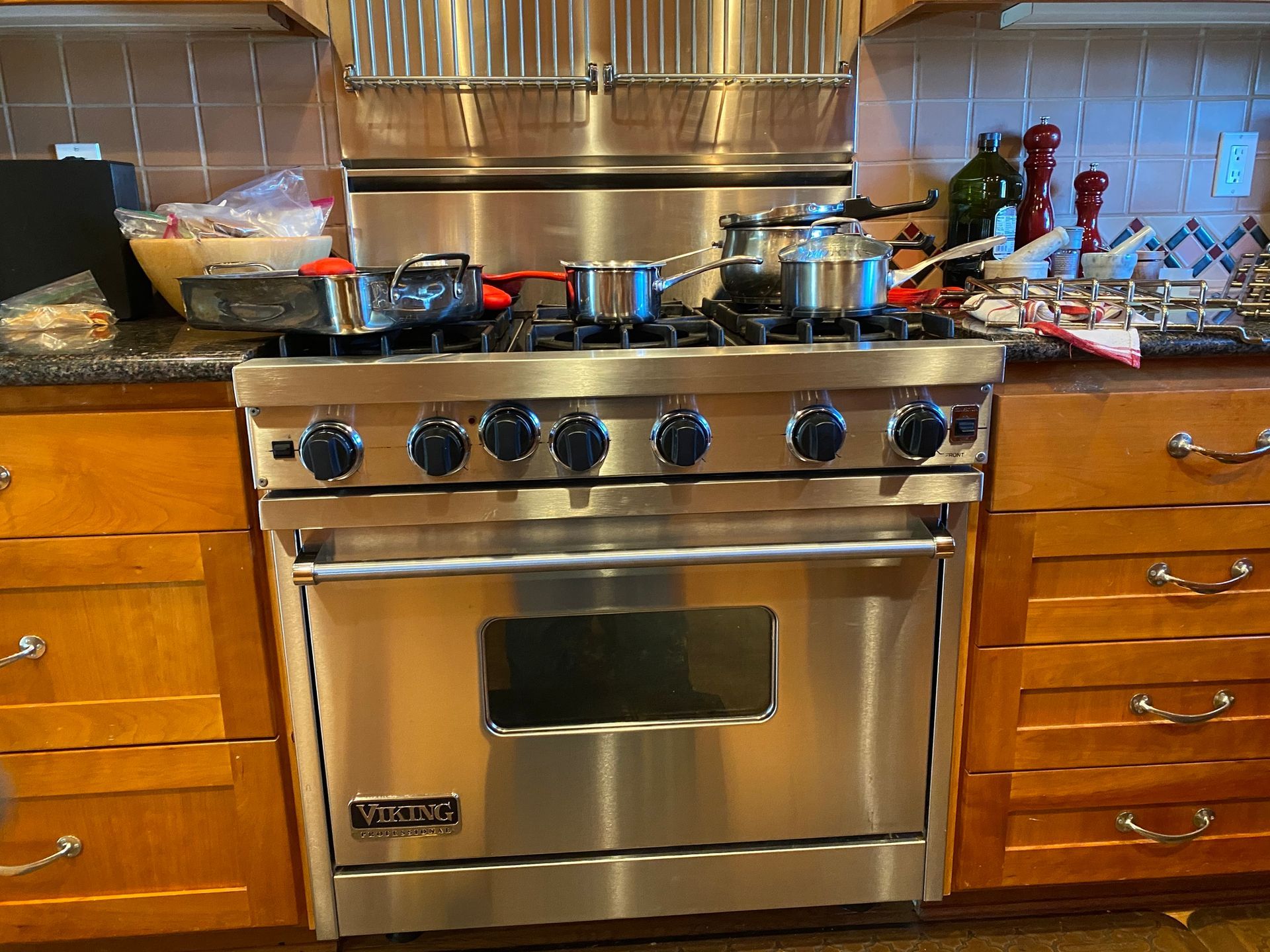 a stainless steel stove in a kitchen with pots and pans on it