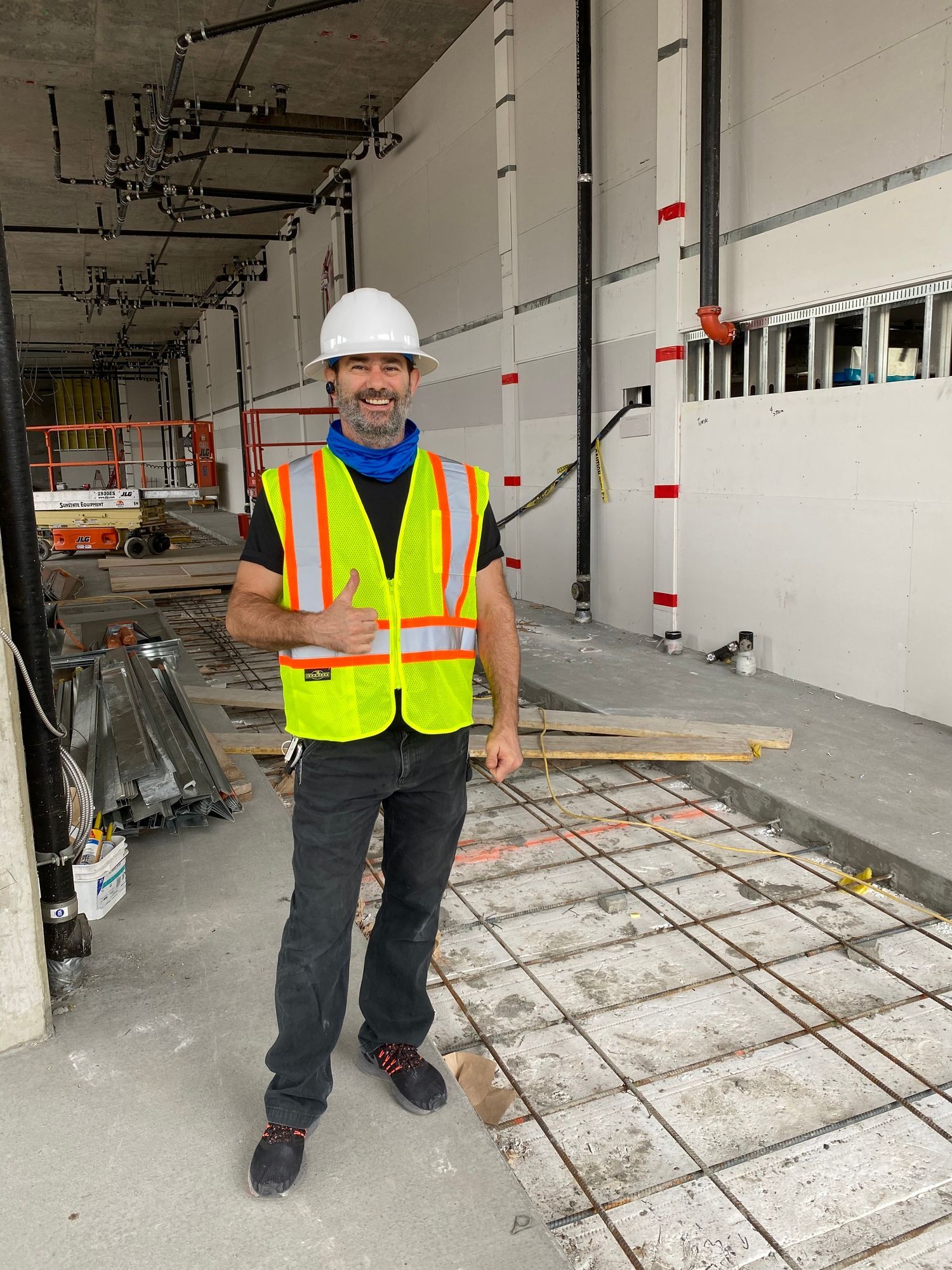 a man wearing a hard hat and safety vest is standing in a building under construction .