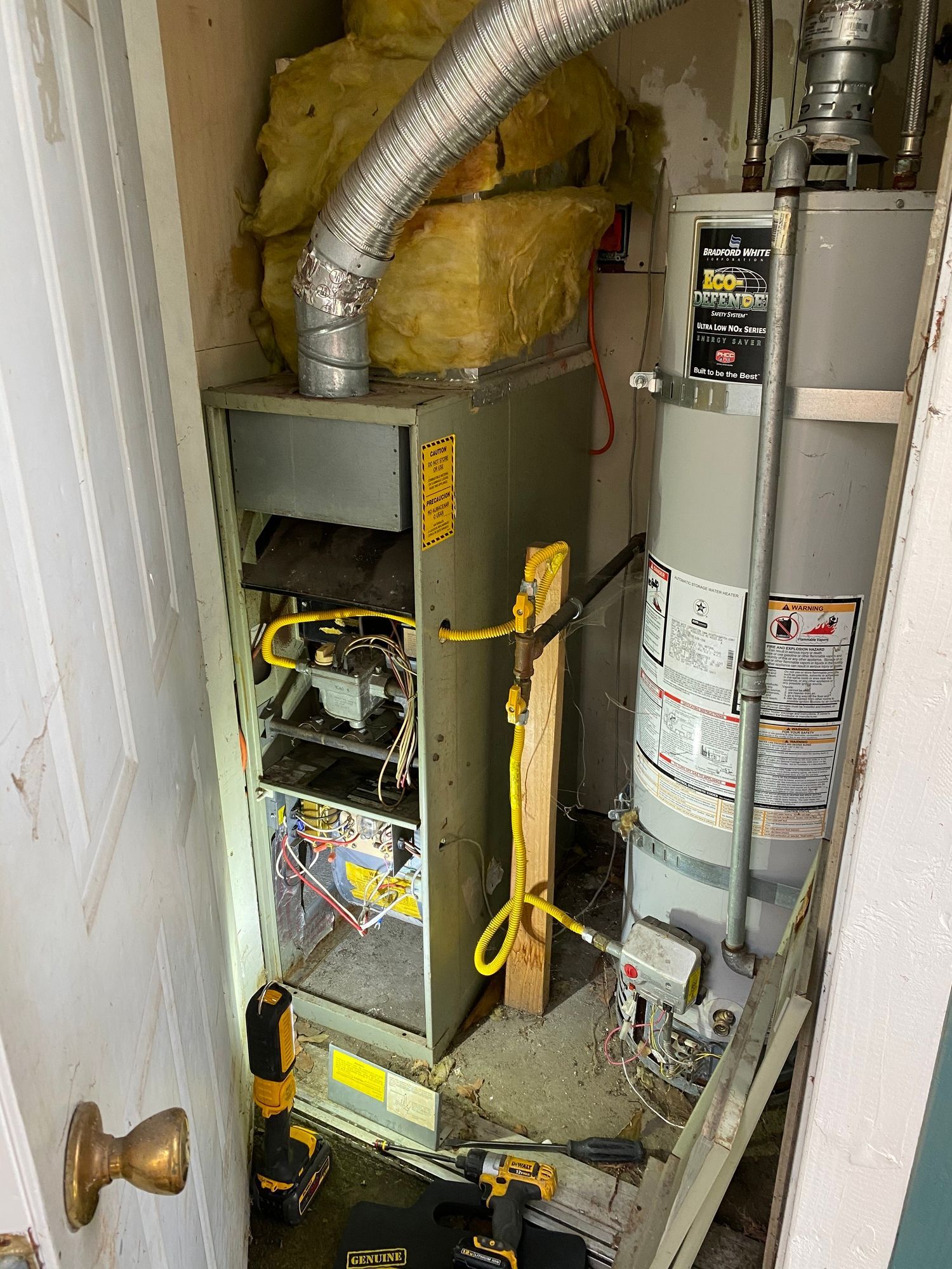 a water heater is sitting in a closet next to a furnace .