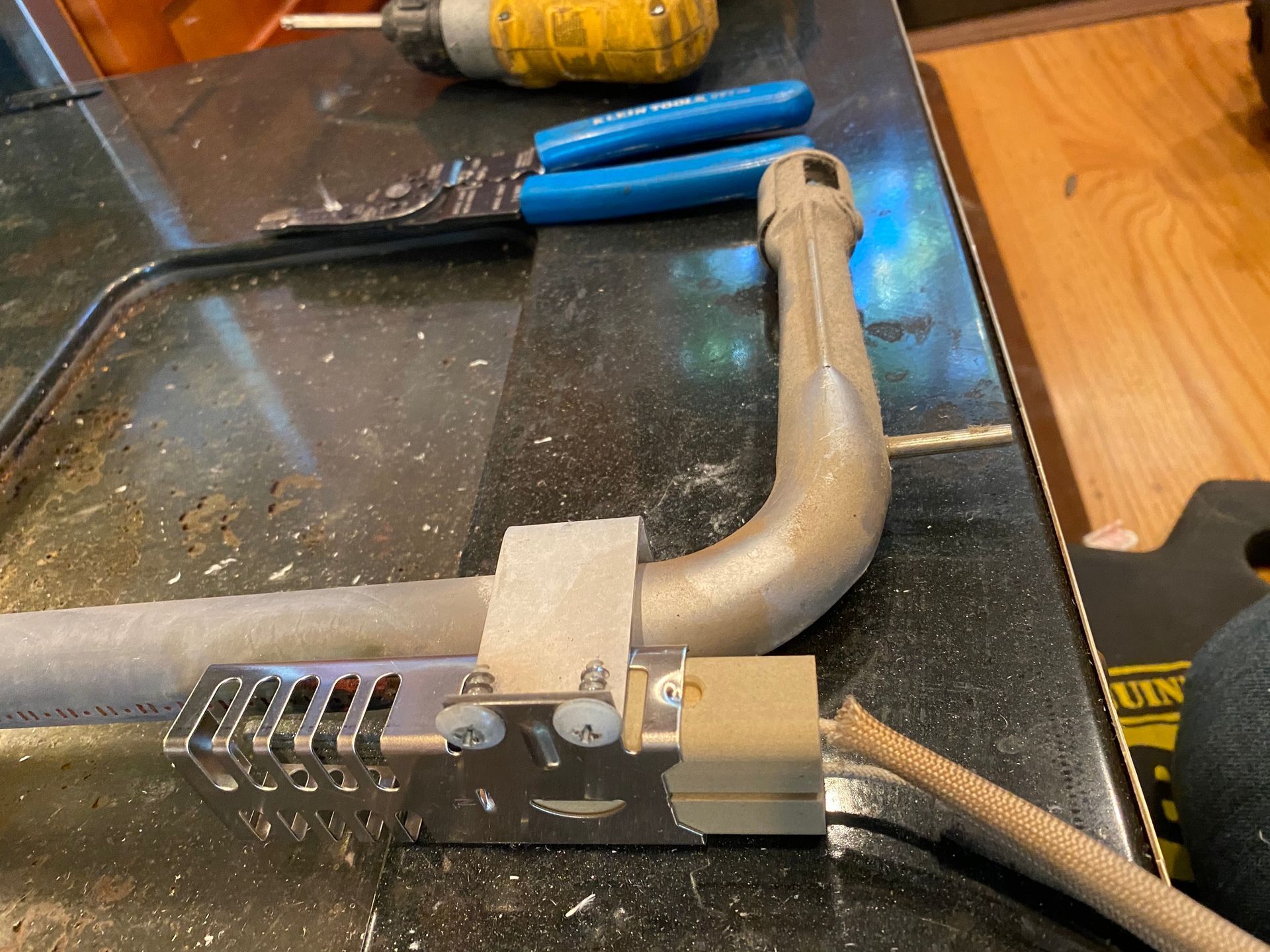 a piece of metal is sitting on a counter next to a pair of pliers .