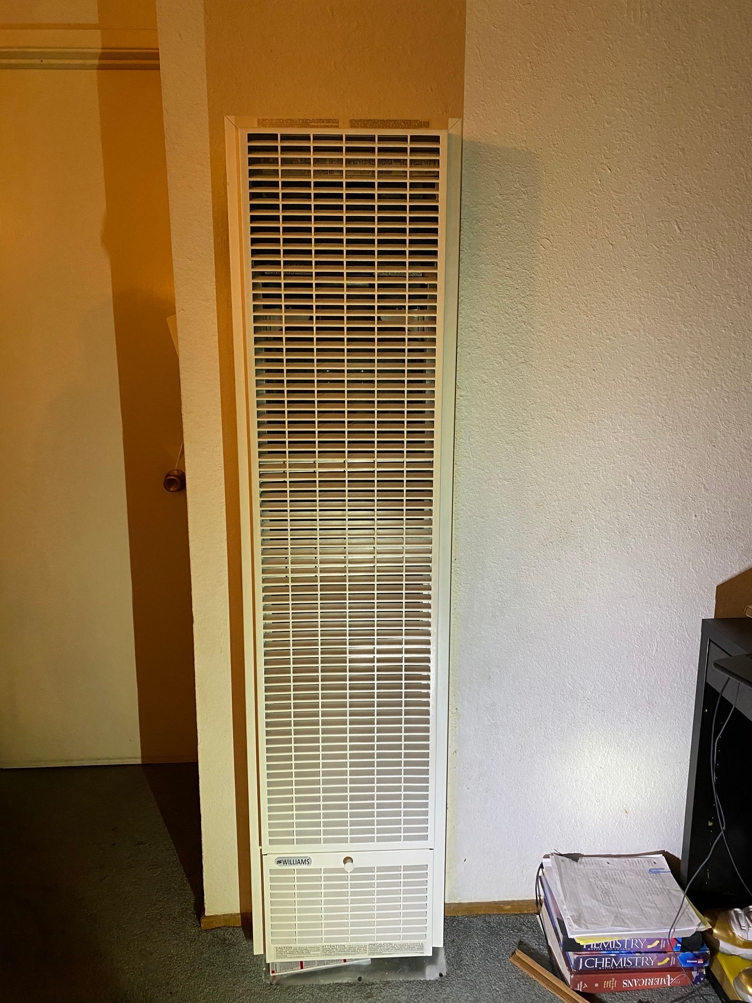 a white heater is sitting in a room next to a door .