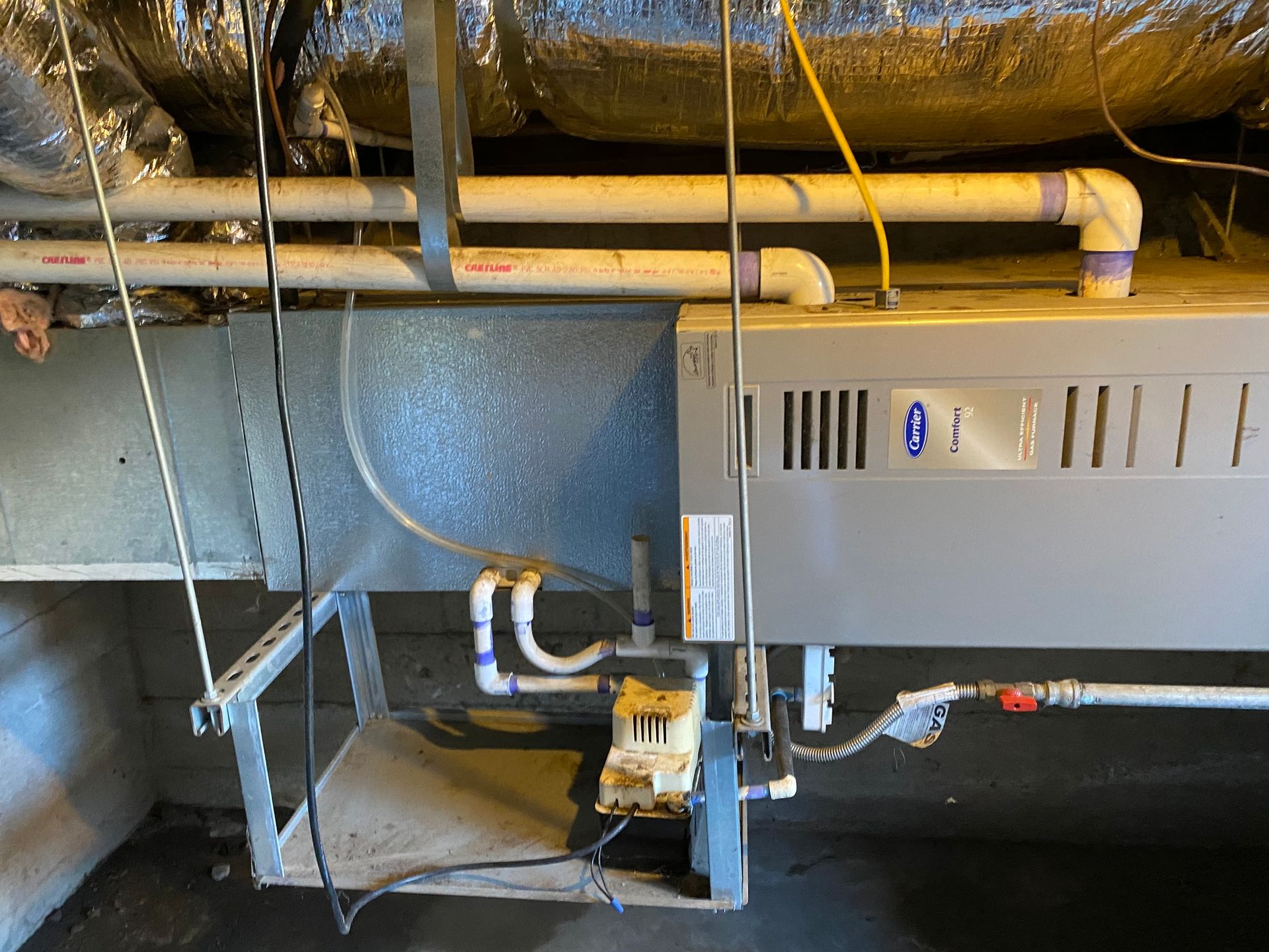 a heater is sitting under a ceiling in a basement .