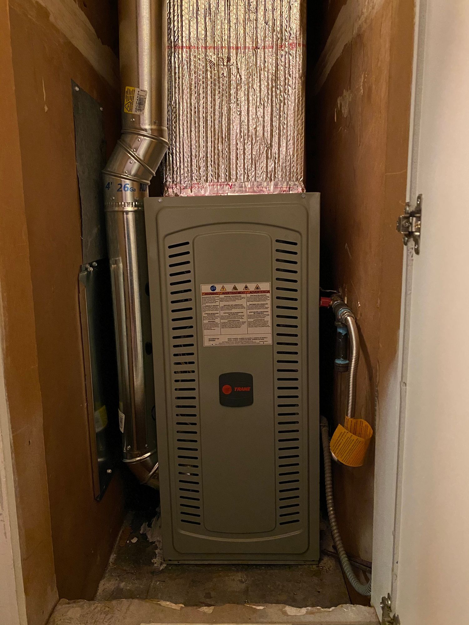 a furnace is sitting in a narrow room next to a door .