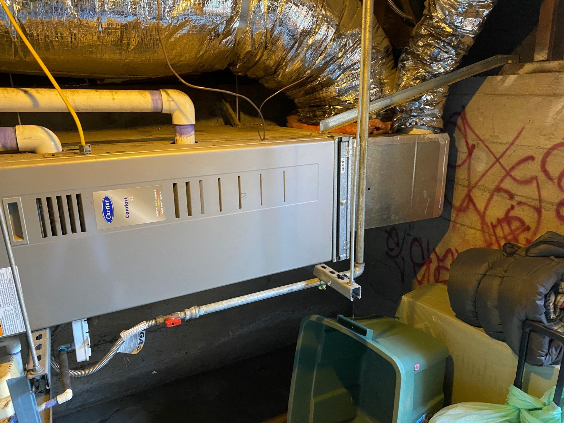 a heater is sitting under a ceiling in a basement .