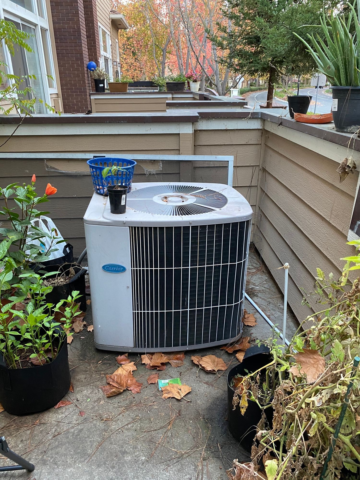 an air conditioner is sitting on a patio next to potted plants .