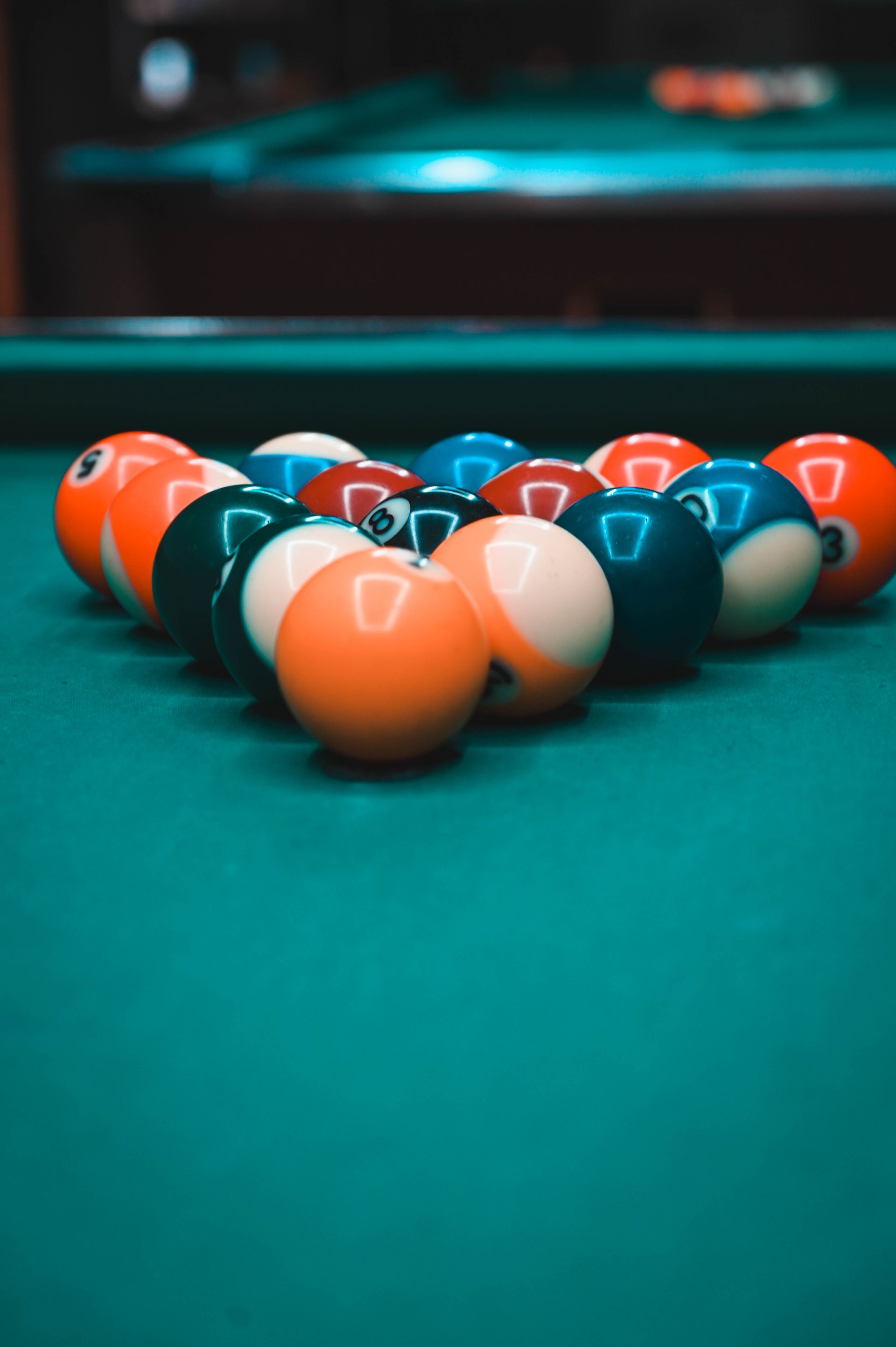 A man is sitting on a pool table holding a pool cue.