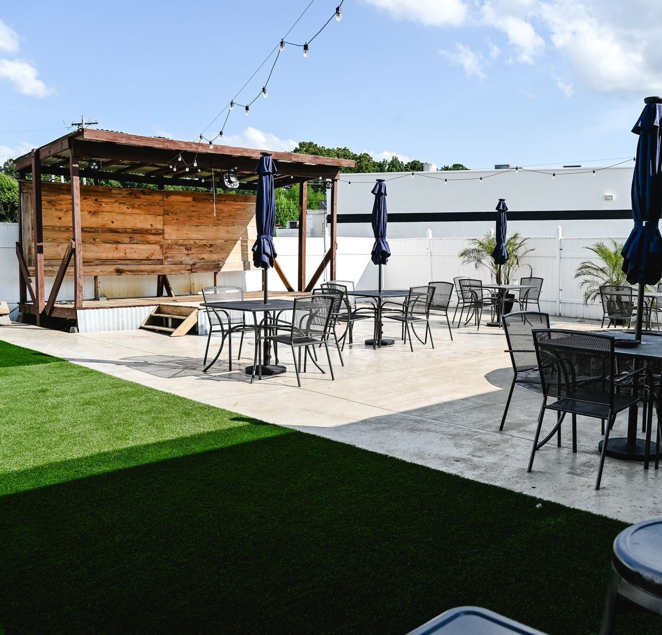 A patio with tables and chairs and umbrellas in front of a building.