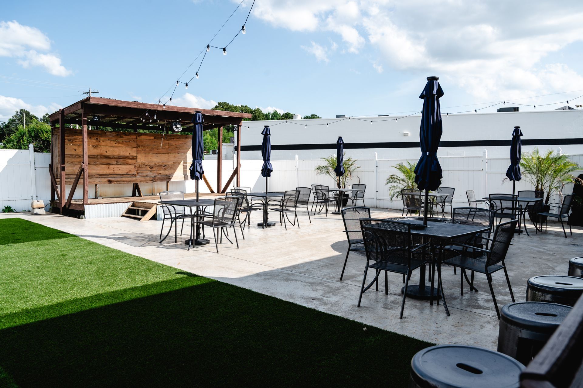 A patio with tables and chairs and umbrellas in front of a building.
