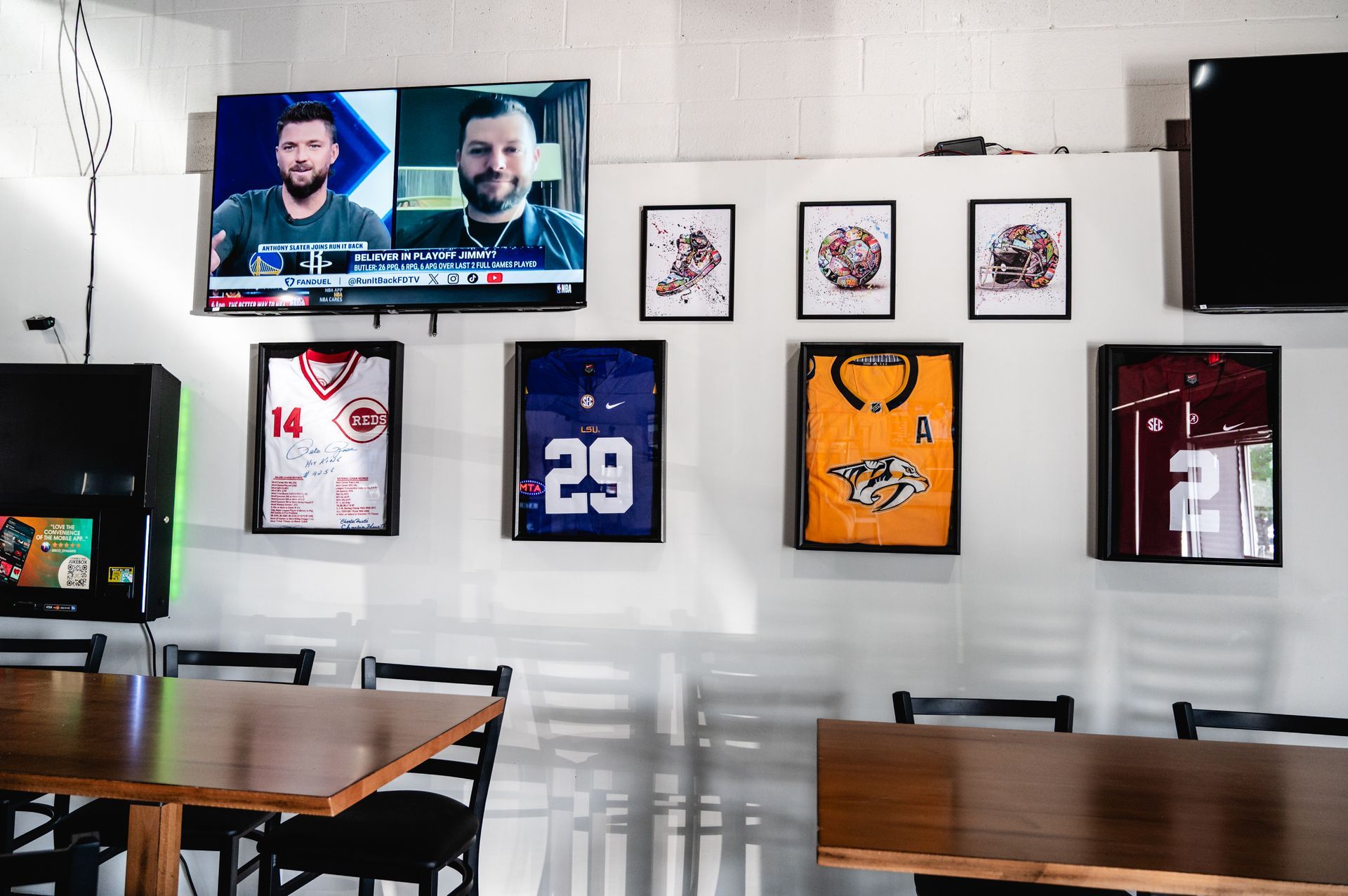 A restaurant with tables and chairs and a television on the wall.