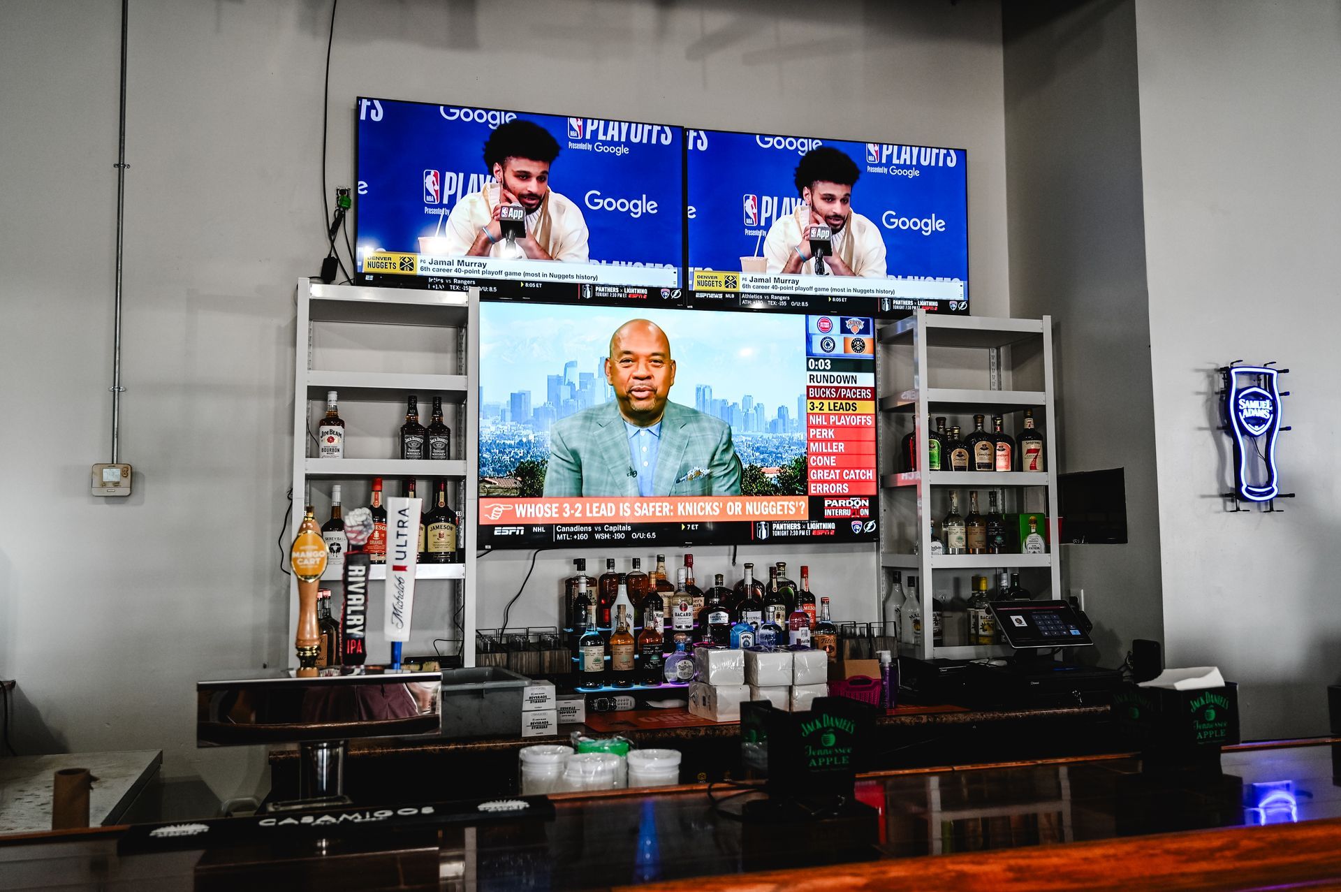 A bar with a large screen displaying a news report