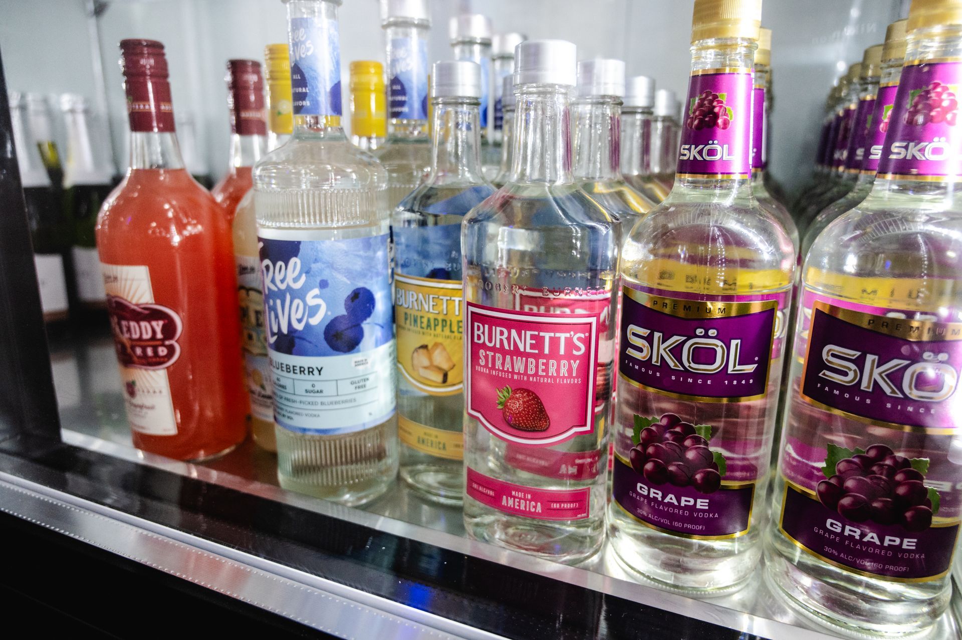 A variety of liquor bottles are lined up on a shelf.