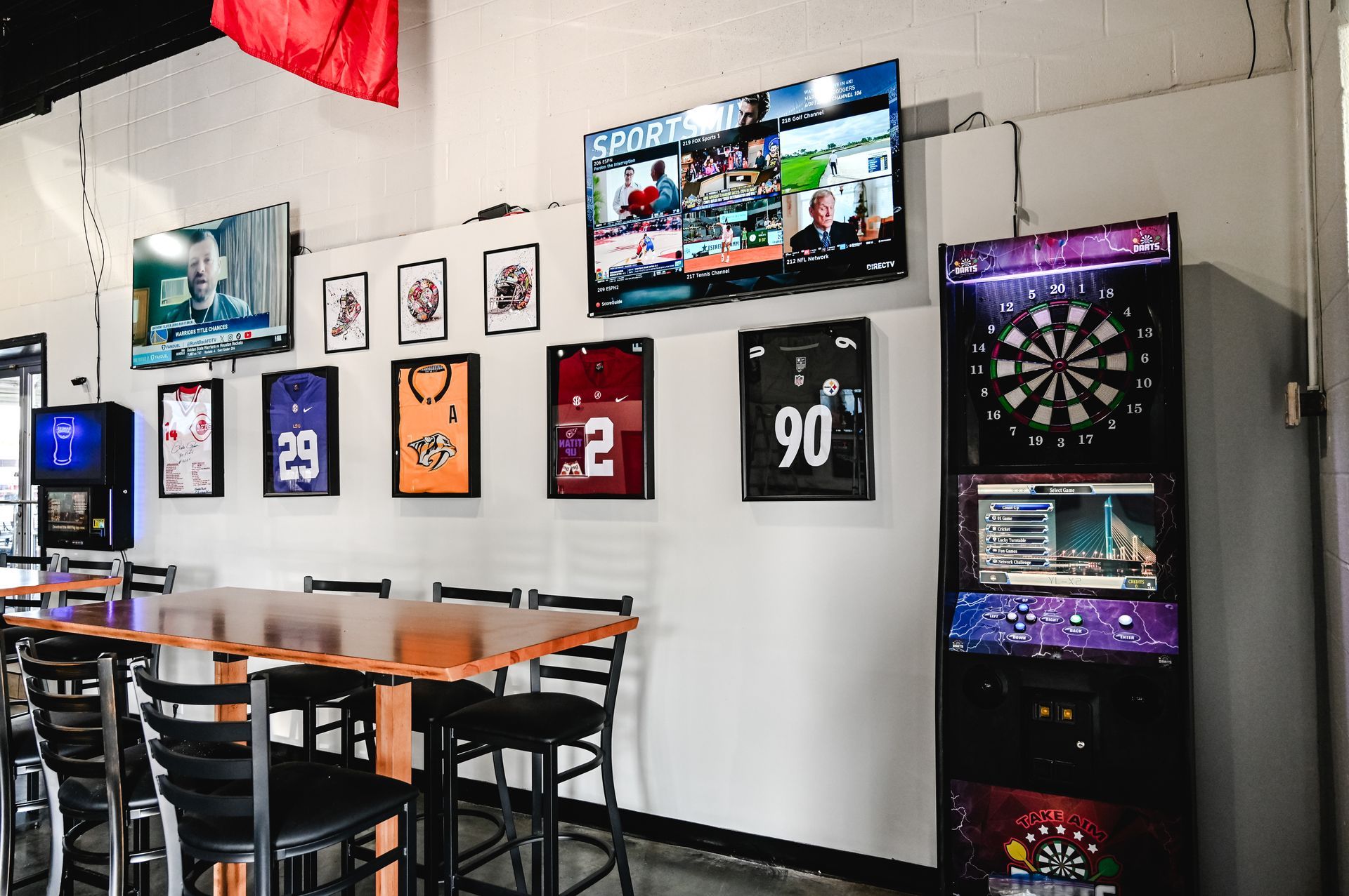 A restaurant with tables and chairs and a dart board.