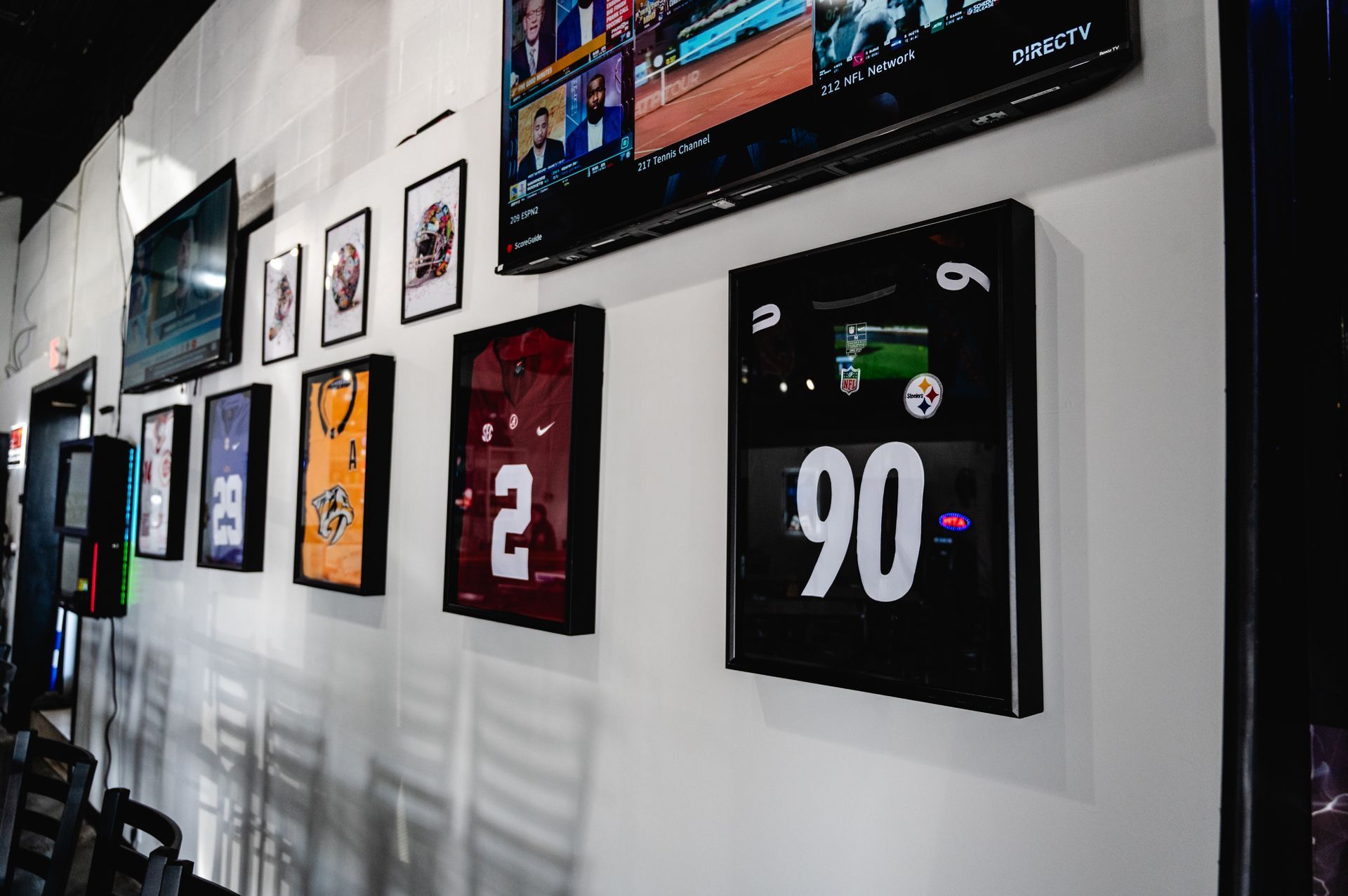 A row of framed jerseys are hanging on a wall.