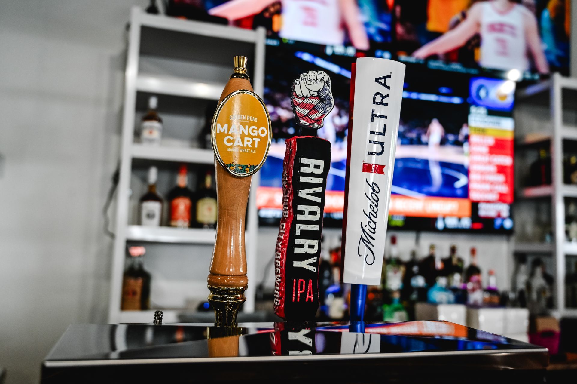 Two beer taps are sitting on a bar counter in front of a television.