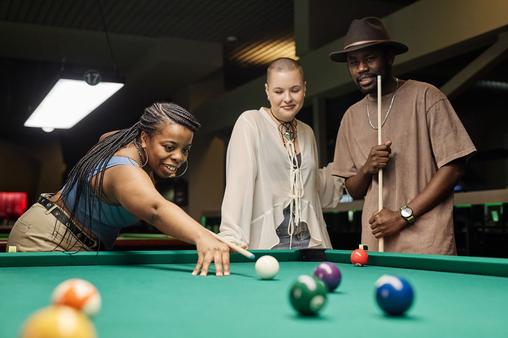 A group of people are playing pool together in a pool hall.