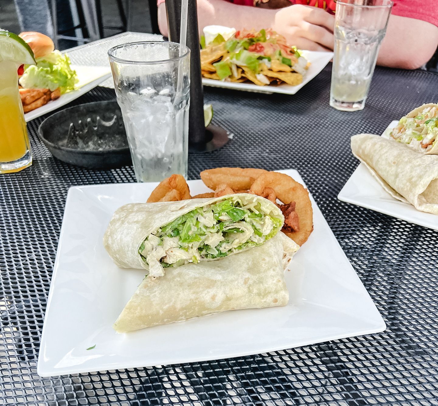 A white plate topped with a wrap and french fries on a table.