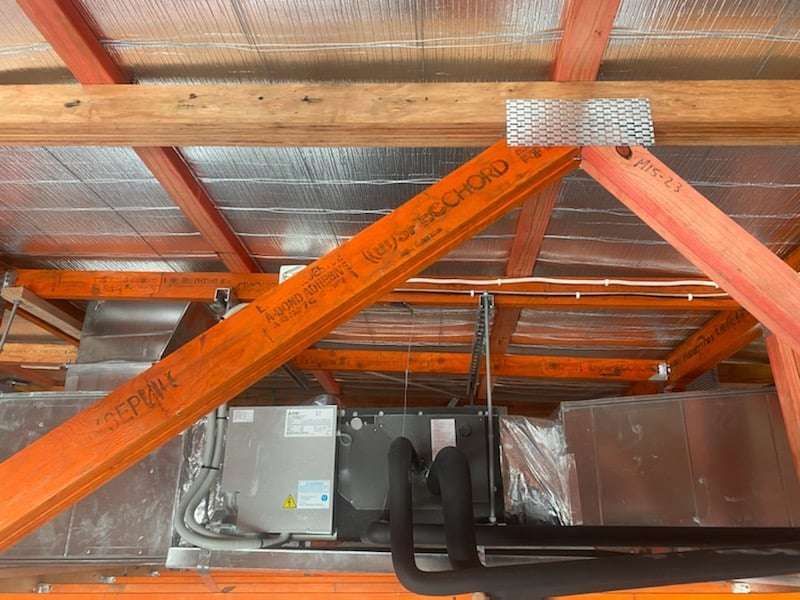 A Ceiling with Wooden Beams and Pipes Hanging from It — McGuire Air & Refrigeration In Paget, QLD