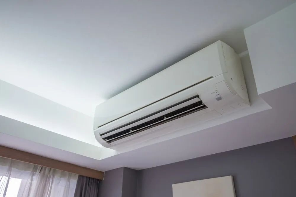 A White Air Conditioner Is Hanging from The Ceiling in A Bedroom — McGuire Air & Refrigeration In Paget, QLD