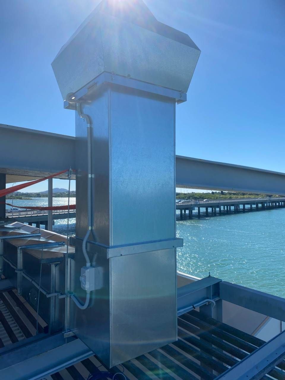 A Metal Chimney on Top of A Building Next to A Body of Water — McGuire Air & Refrigeration In Paget, QLD