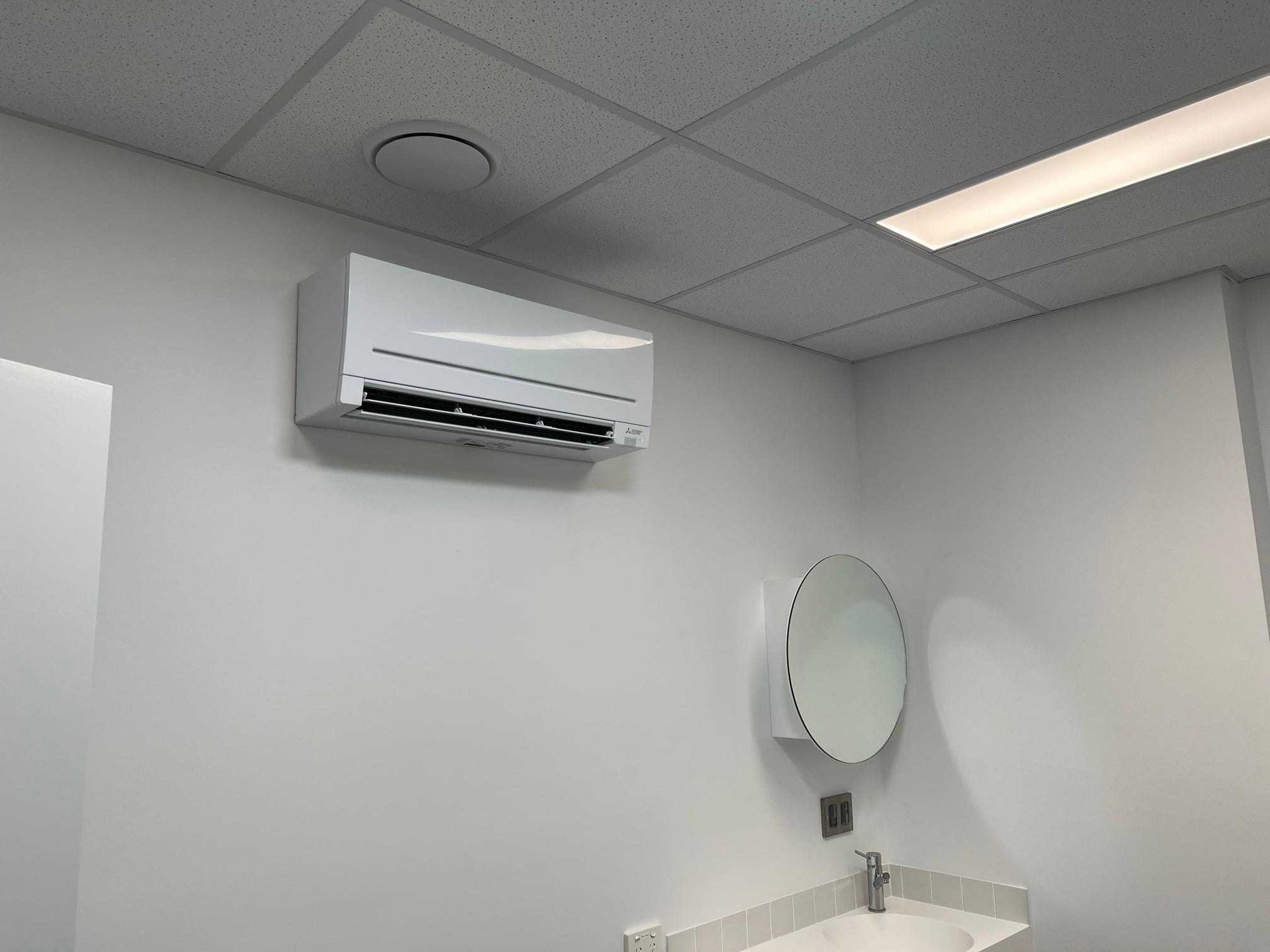 A Bathroom with A Sink, Mirror and Air Conditioner — McGuire Air & Refrigeration In Paget, QLD