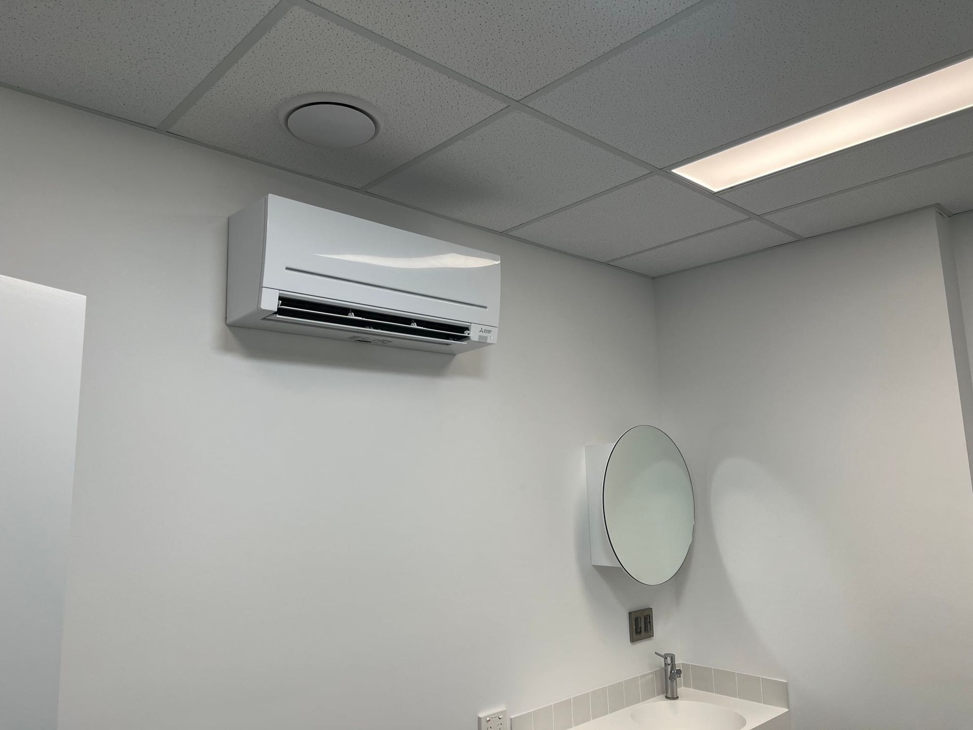 A Person Is Holding a Remote Control in Front of An Air Conditioner — McGuire Air & Refrigeration In Paget, QLD