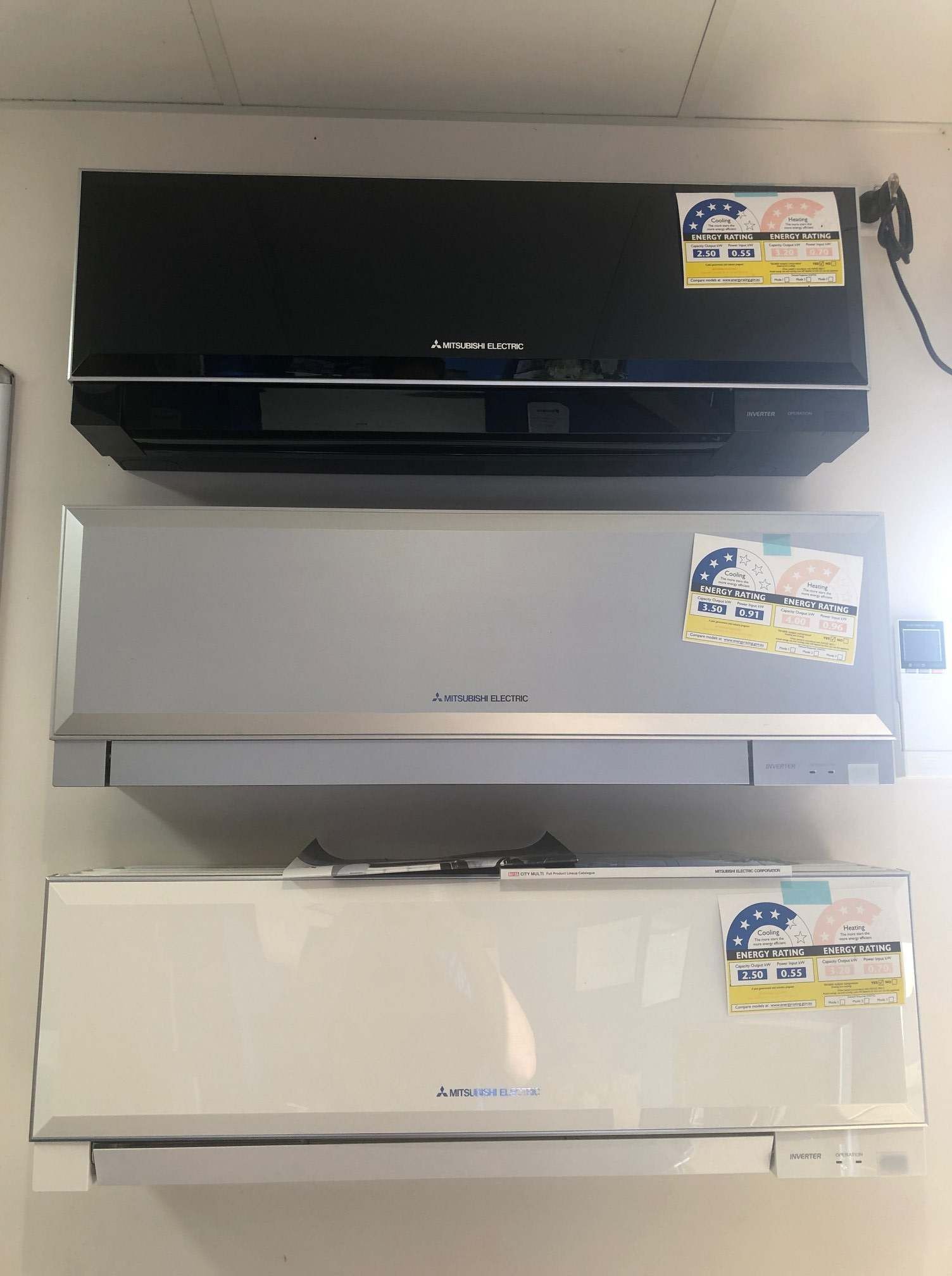 Three Air Conditioners Are Lined up On a Wall — McGuire Air & Refrigeration In Paget, QLD