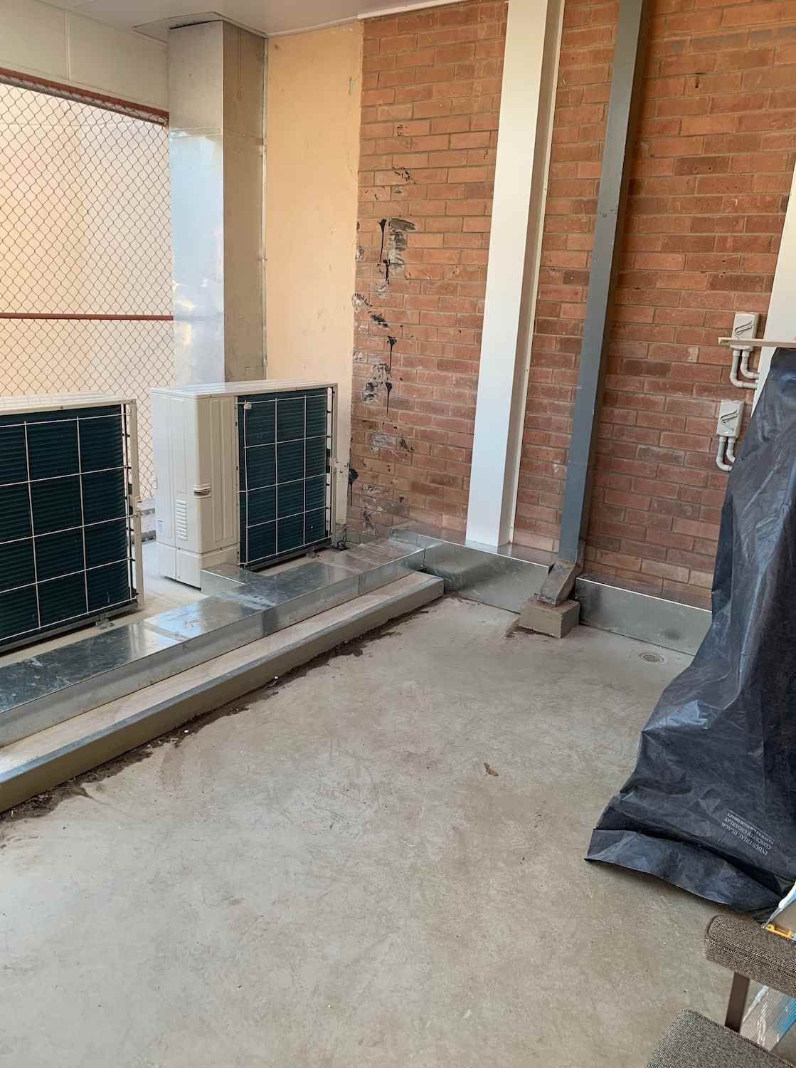 A Room with A Brick Wall and Two Air Conditioners in It — McGuire Air & Refrigeration In Paget, QLD