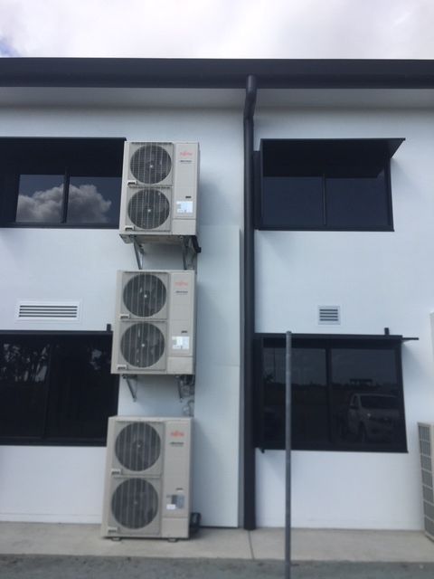 Three Air Conditioners Are Stacked on The Side of A Building — McGuire Air & Refrigeration In Paget, QLD