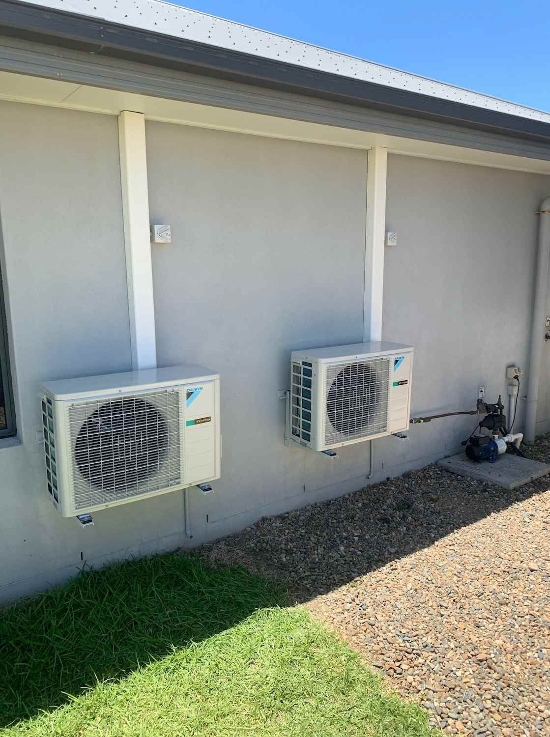 Two Air Conditioners Are Mounted on The Side of A House — McGuire Air & Refrigeration In Paget, QLD