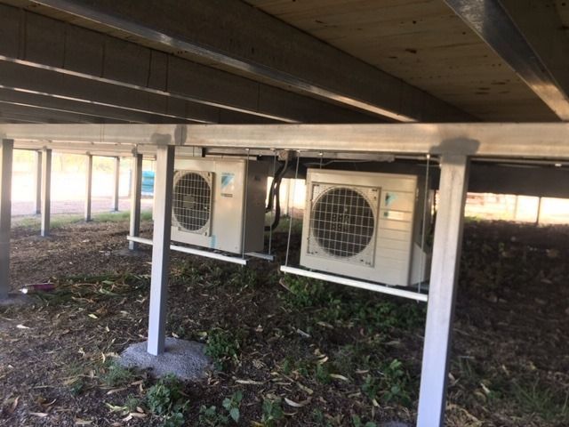 Two Air Conditioners Are Sitting Under a Bridge — McGuire Air & Refrigeration in Moranbah, QLD