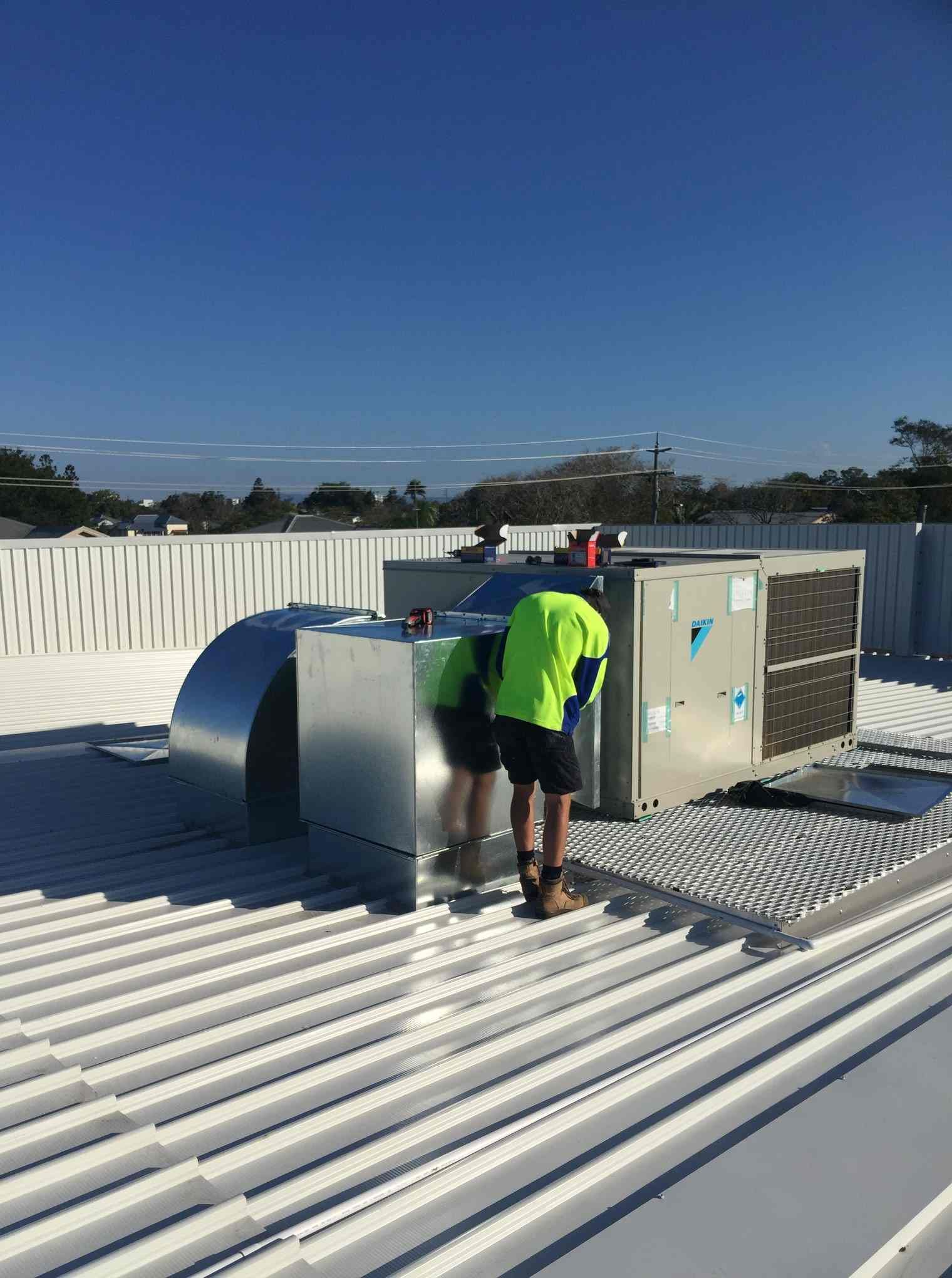 Two Men Are Working on The Roof of A Building — McGuire Air & Refrigeration In Paget, QLD
