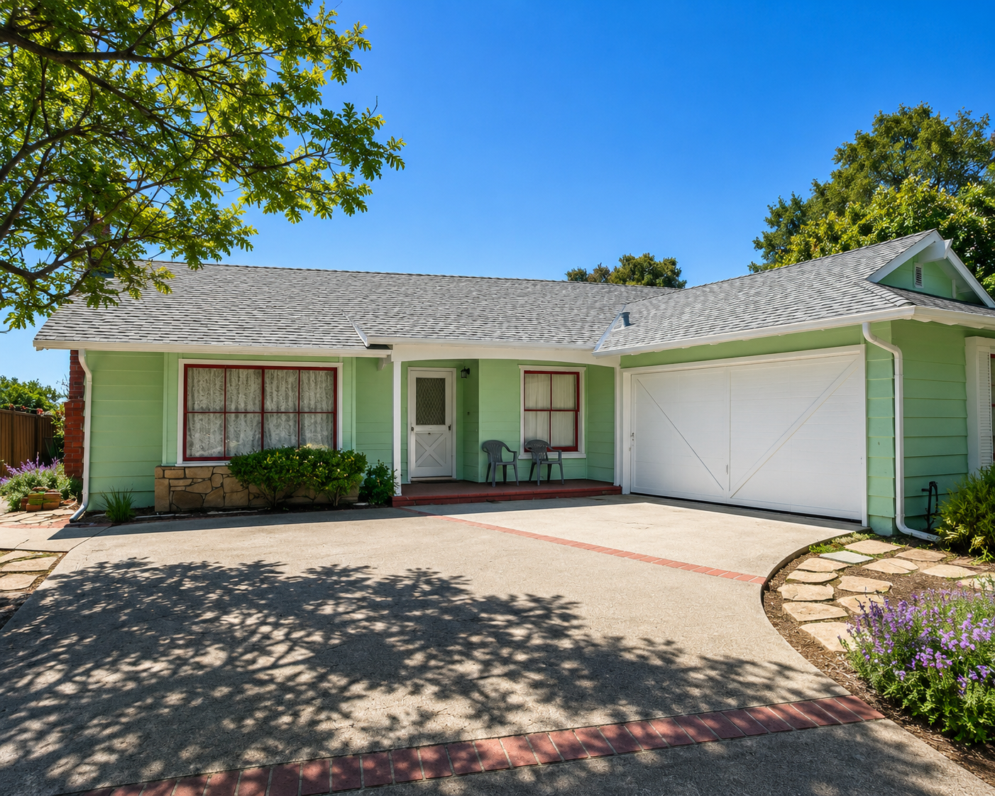 Single-story mint-green house with a white garage, front porch, and wide driveway under sunny skies
