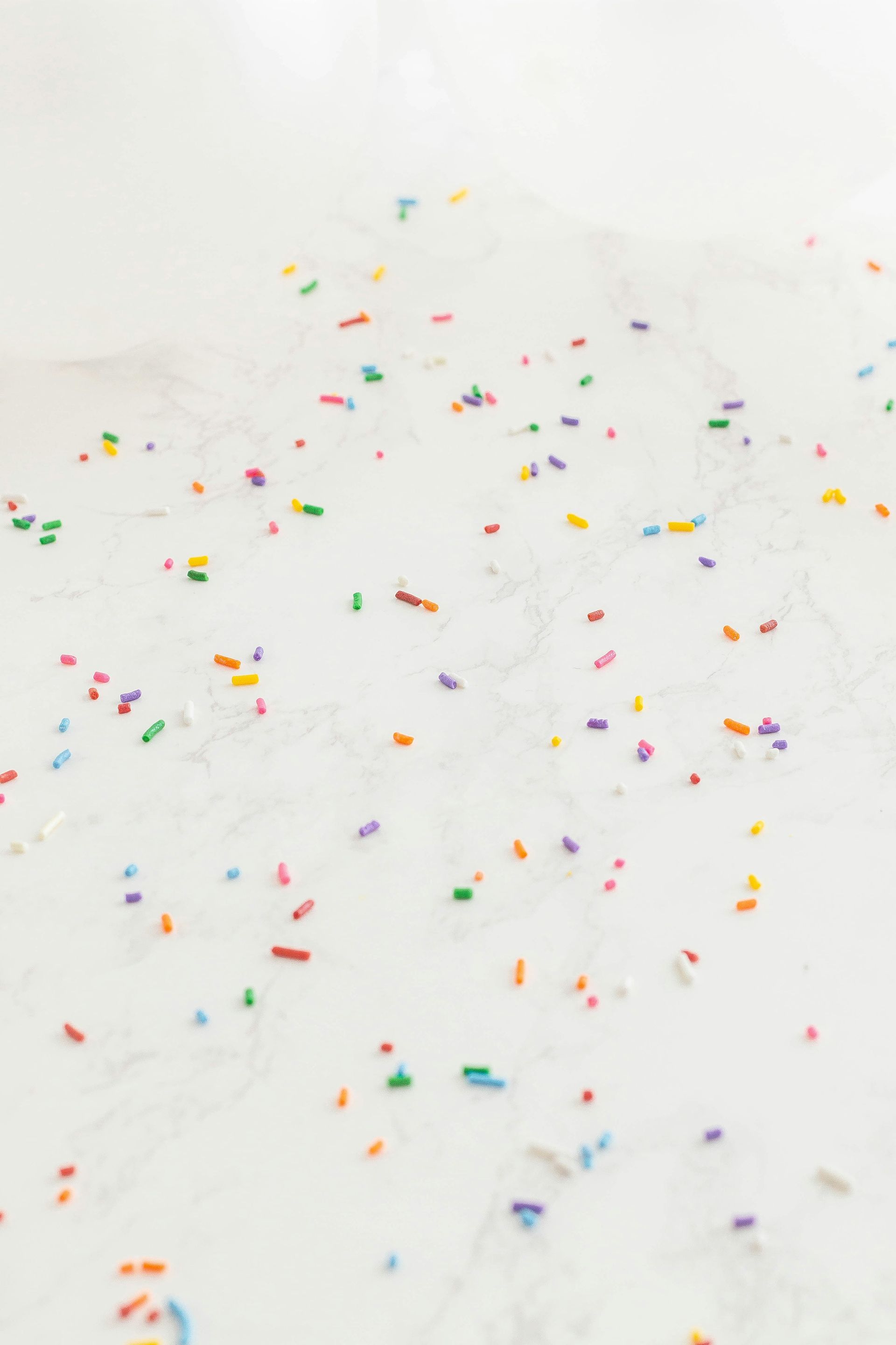 A close up of a white surface with colorful sprinkles on it to represent molloscum bumps.