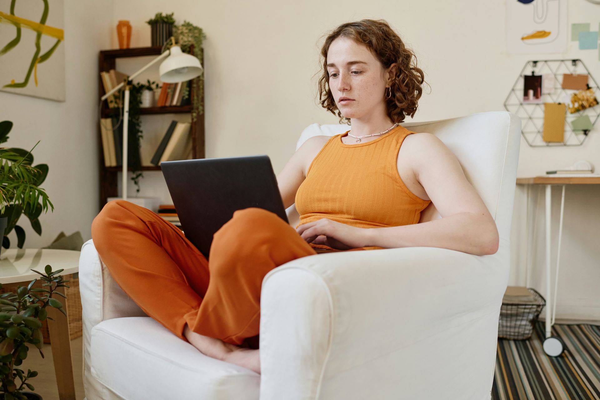A woman in an orange outfit logs on to her laptop for a virtual sex therapy session. 