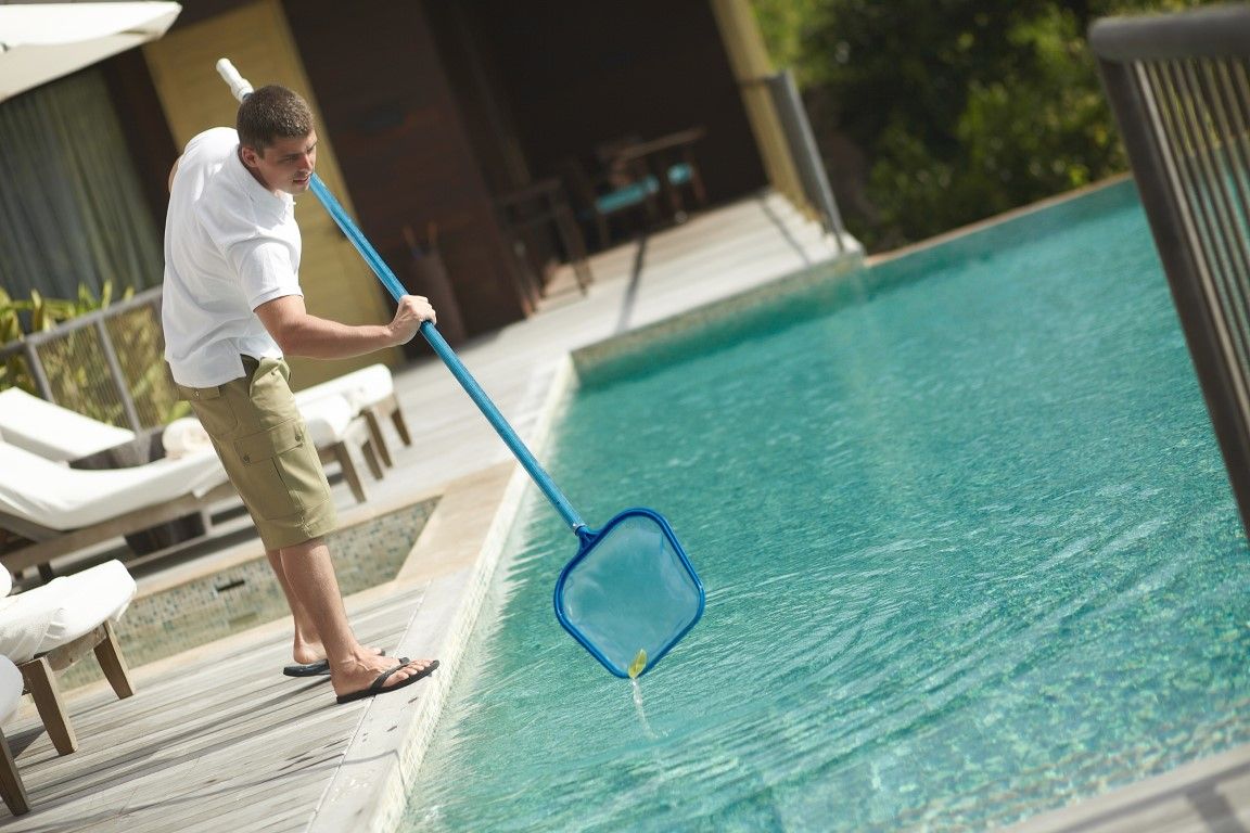 A man is cleaning a swimming pool with a net
