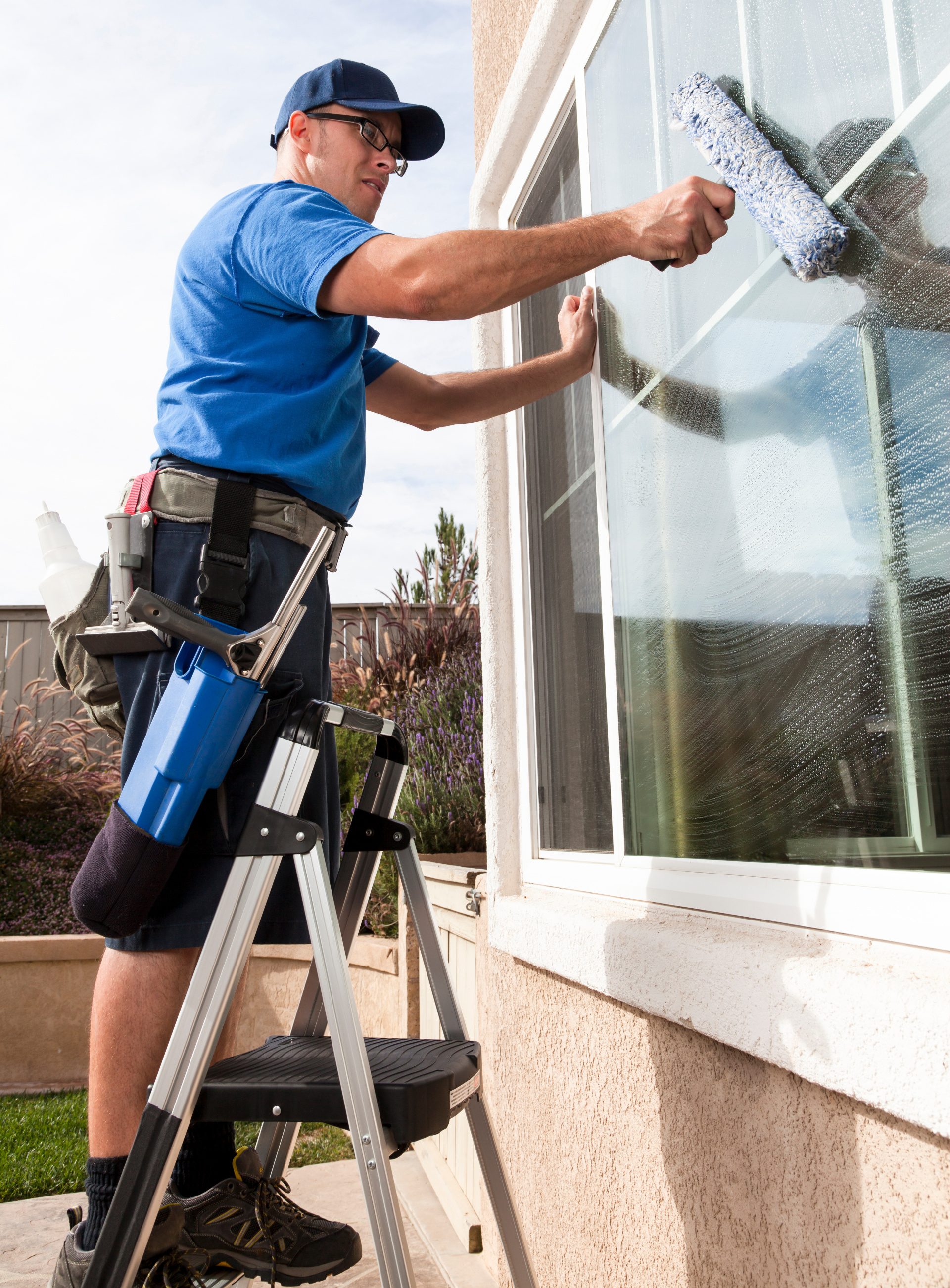 A man is standing on a ladder cleaning a window.