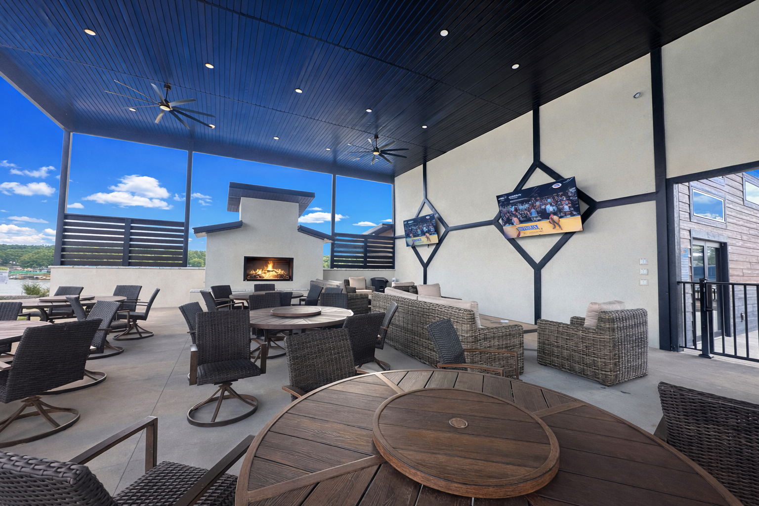 Poolside pavilion with lounge chairs, tables, and a pool. Black and white building with a blue sky.