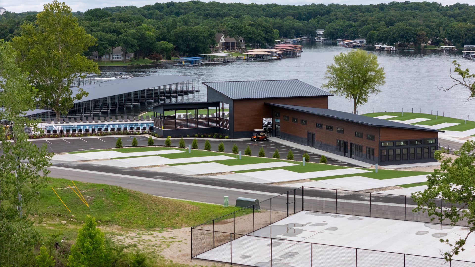 Modern lakefront building with docks, trees, and water.
