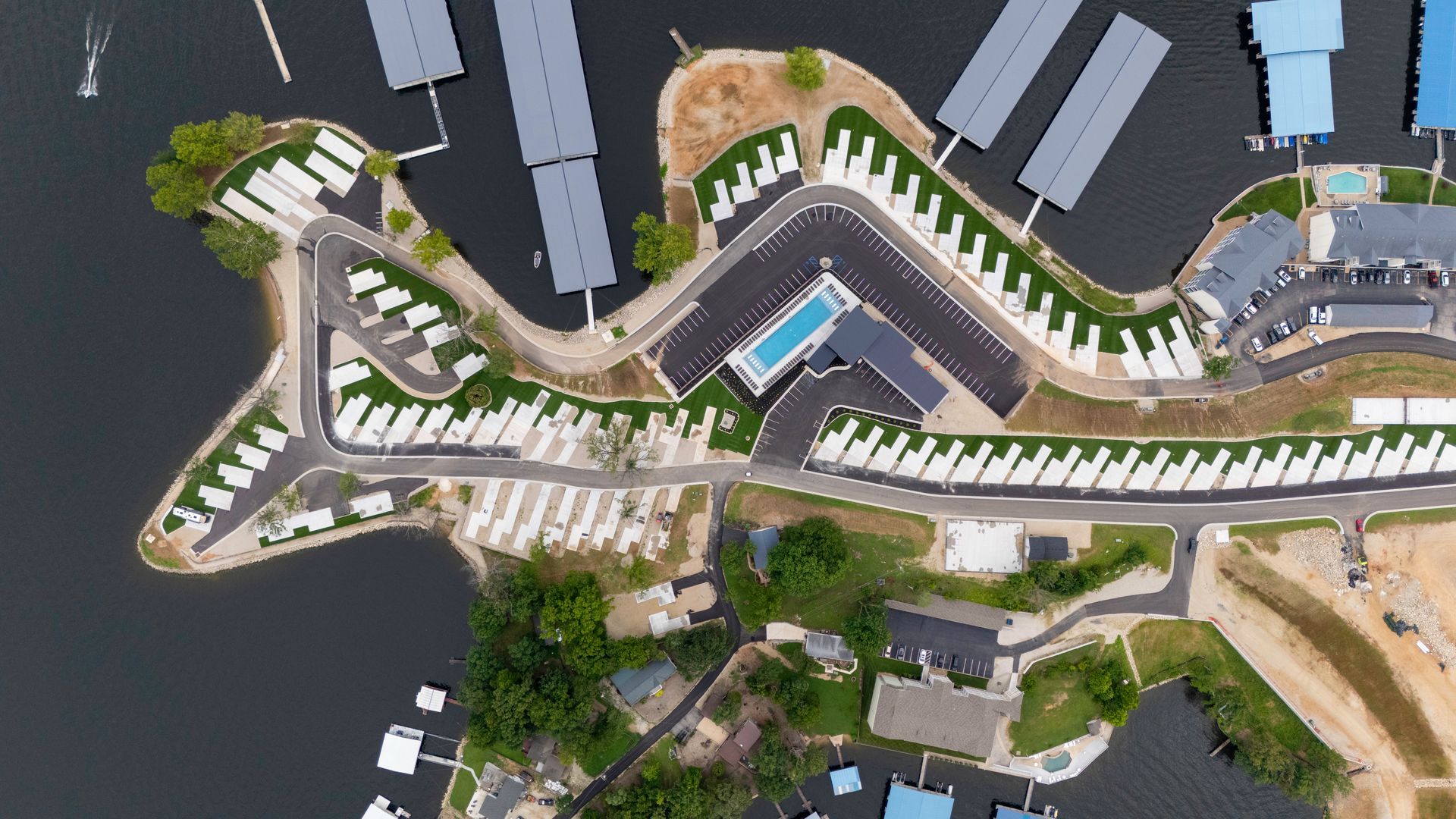 Aerial view of a resort with a pool, docks, and RV parking along a waterfront.