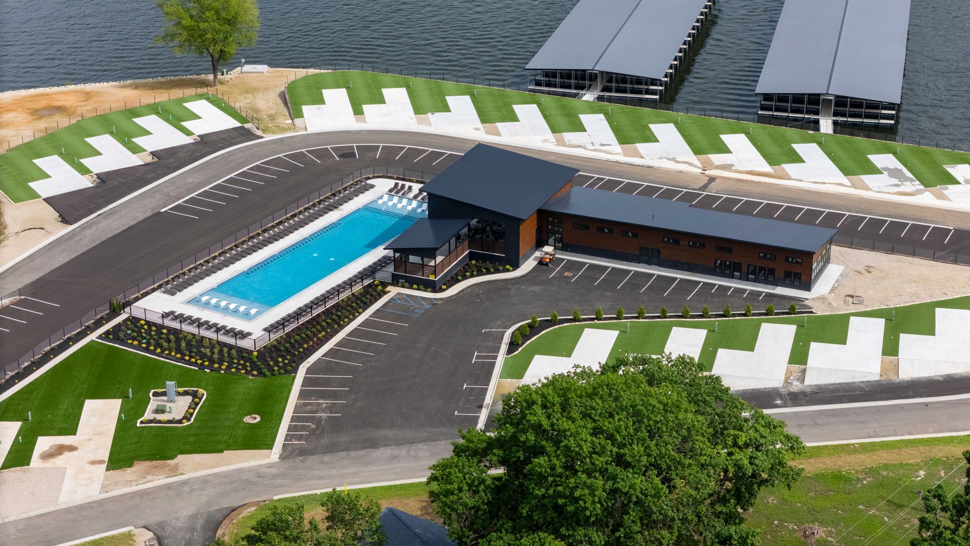 A modern building with pool and parking by a lake with boat docks.