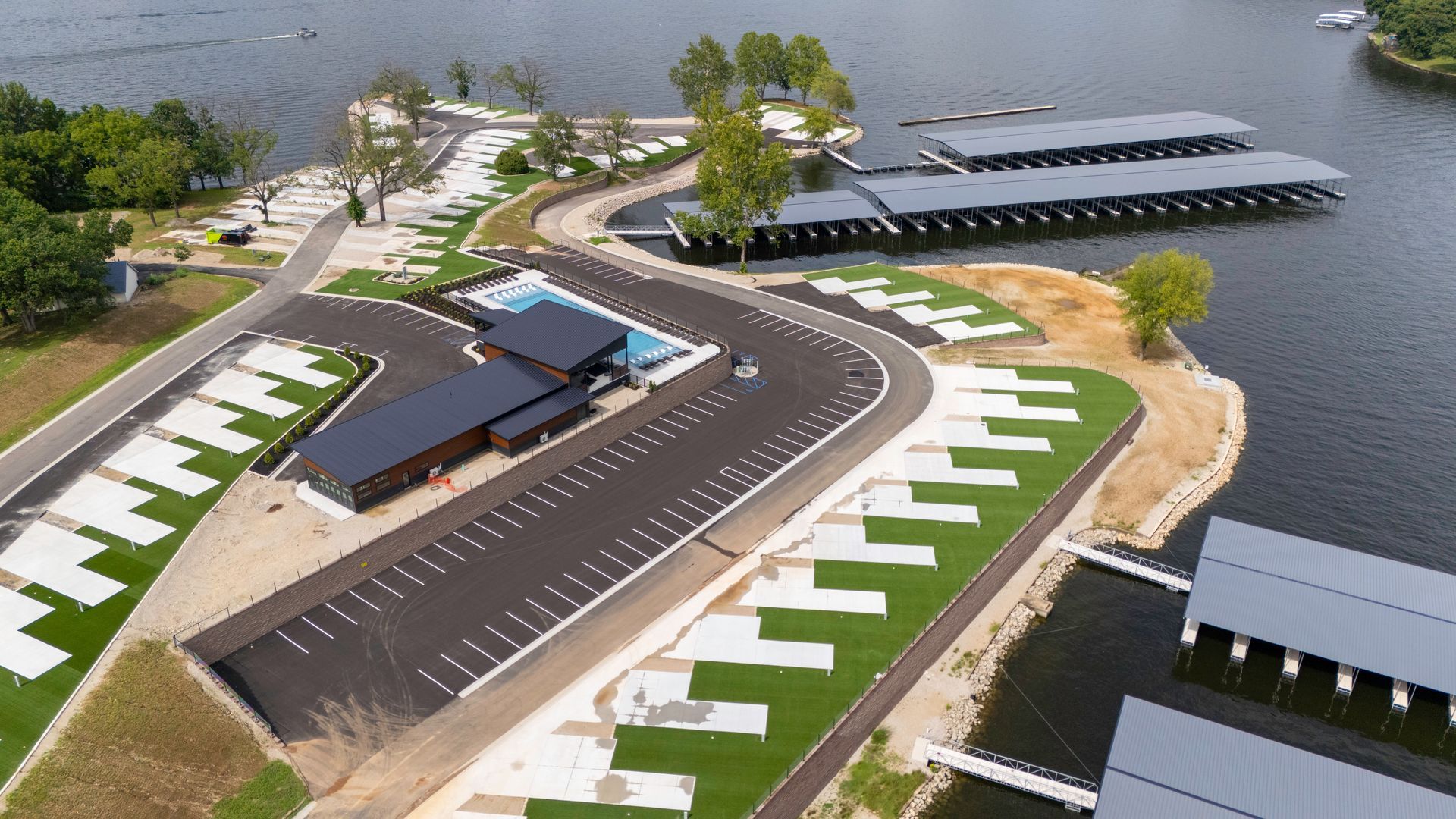 Aerial view of a lakefront resort with a pool, docks, and parking.