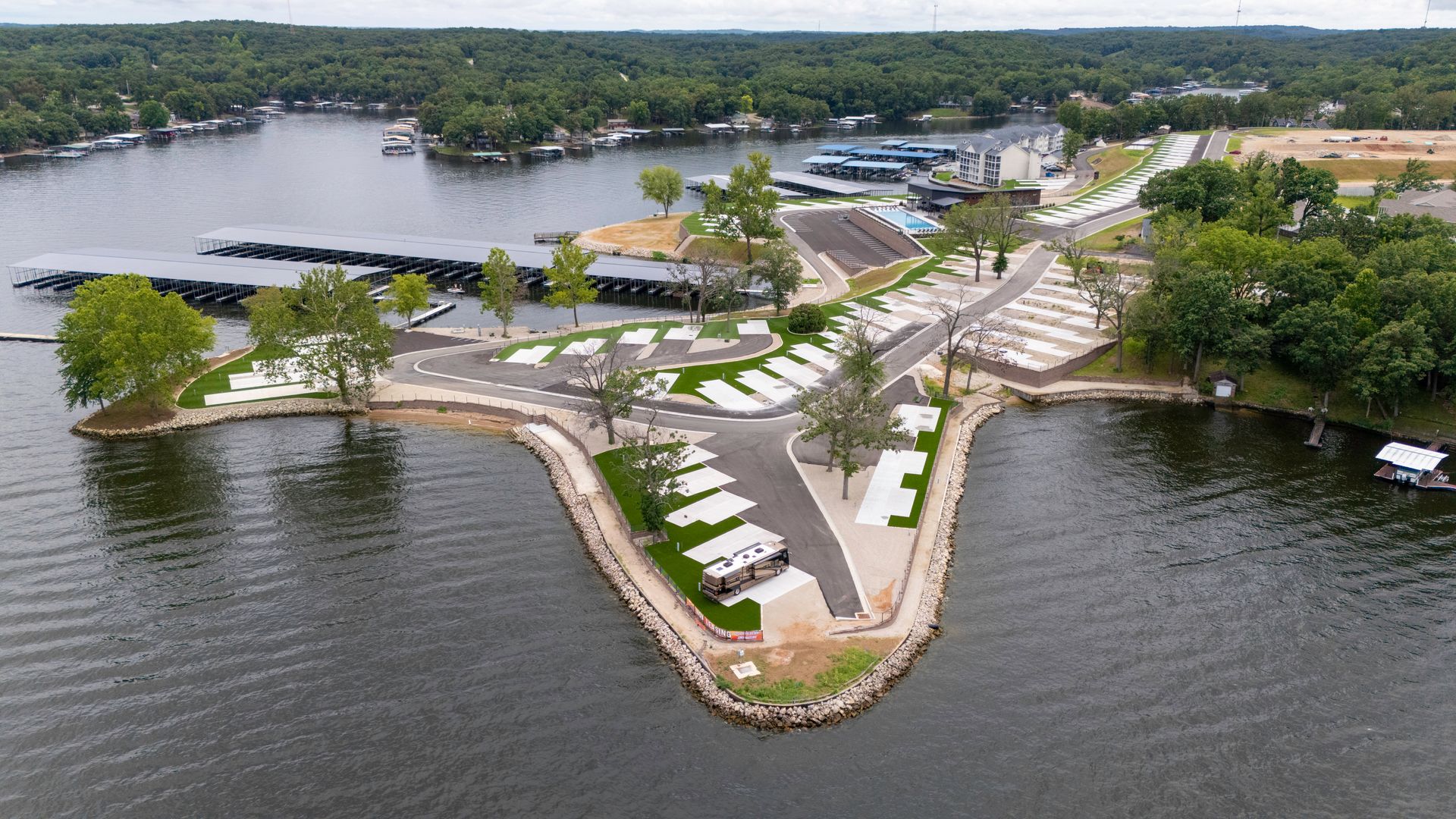 Aerial view of a lakefront RV park with docks, campsites, and trees.