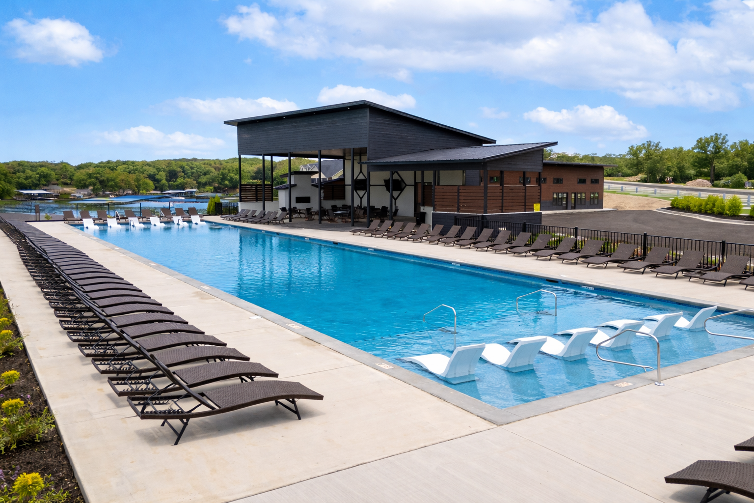 Pool with lounge chairs, a cabana-style bar, and blue sky.