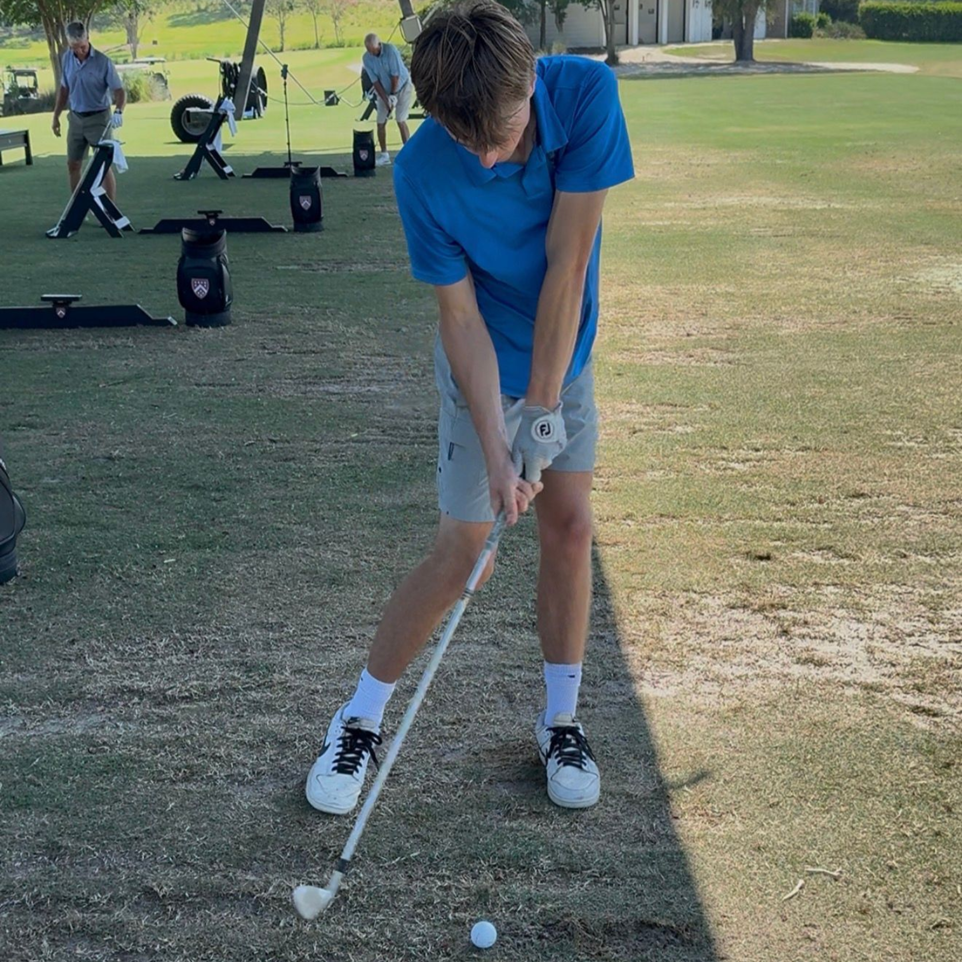 A man is swinging a golf club on a golf course.