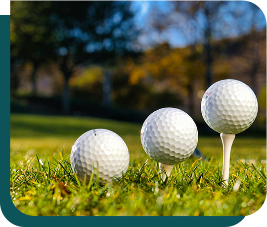 Three golf balls are sitting on a tee in the grass.