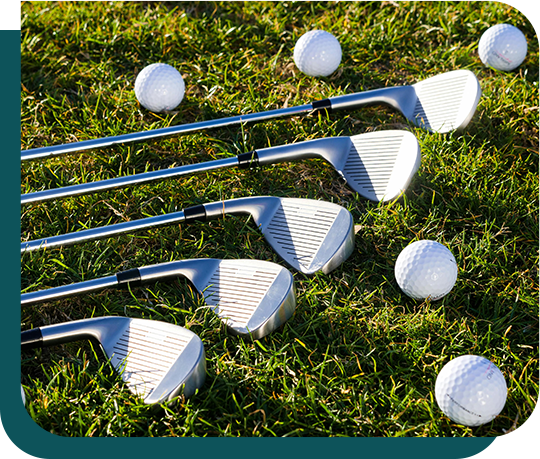 A group of golf clubs and golf balls are laying on the grass.