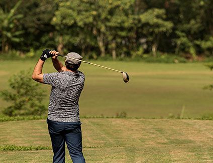 A man is swinging a golf club on a golf course.