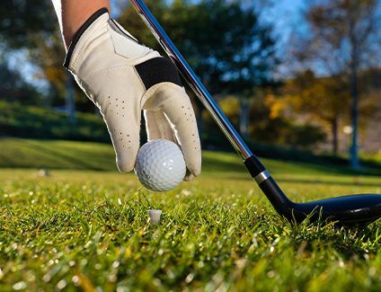 A person is putting a golf ball on a tee.