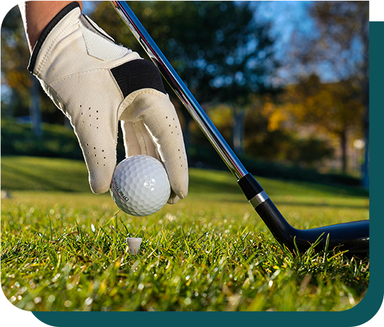 A person is hitting a golf ball with a golf club.