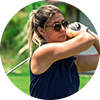 A woman wearing sunglasses is swinging a golf club on a golf course.